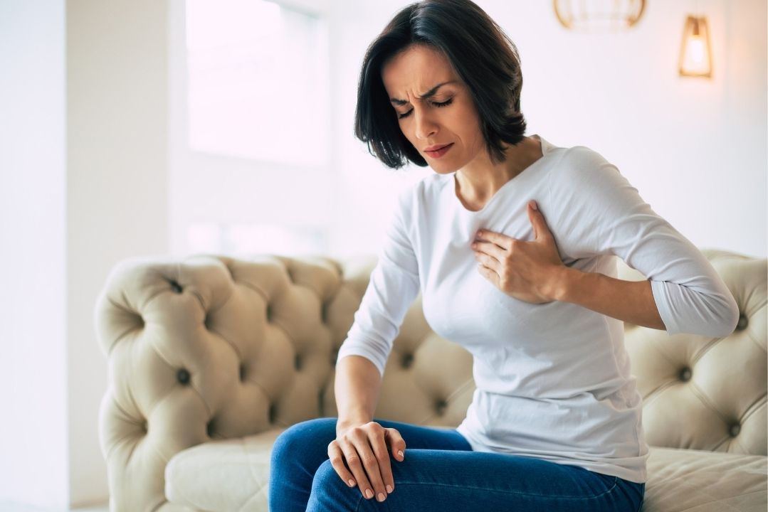 mujer adulta con mano en el pecho por dolor