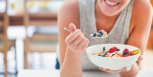 mujer comiendo un bowl sano con frutas